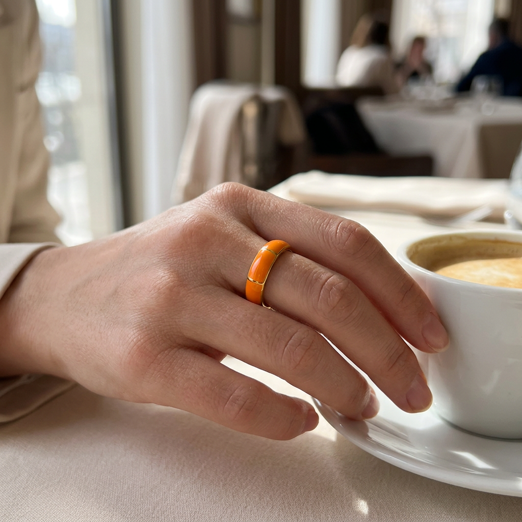 Jeden złoto-pomarańczowy pierścionek na dłoni przy kawie w restauracji