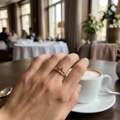 Jeden złoty pierścionek z tiarą na dłoni przy kawie w restauracji