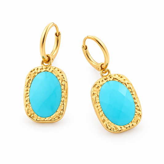 Para złotych kolczyków z turkusowymi kamieniami na białym tle